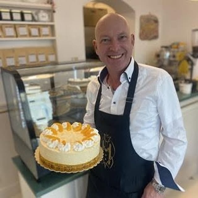 Der Inhaber des Café Mignon mit einer frischen Torte im Lokal