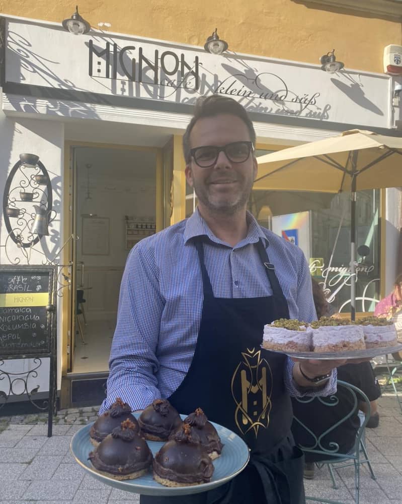 Inhaber und Barista János Dombi mit frischen Mehlspeisen vor dem Café Mignon